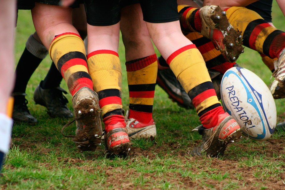 Muddy rugby players' legs and feet during a scrum.