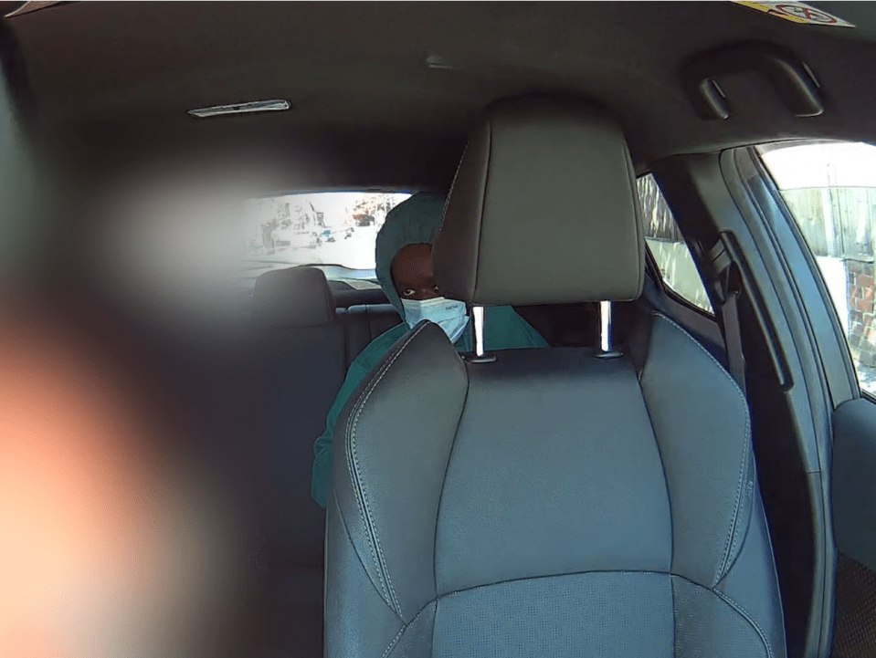 Person wearing a face mask in the backseat of a car.