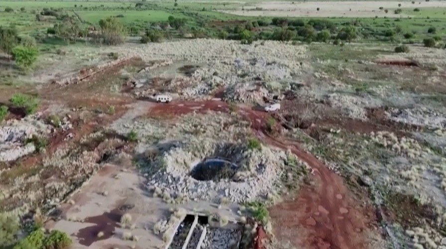 Aerial view of a quarry with two vehicles.