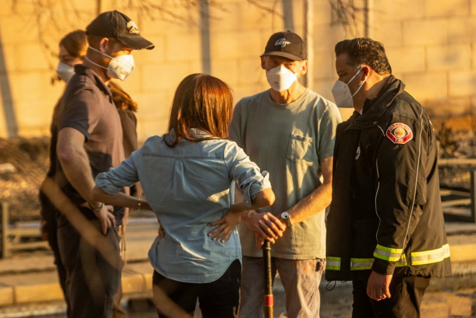 Meghan Markle speaking with officials at a fire-damaged site.