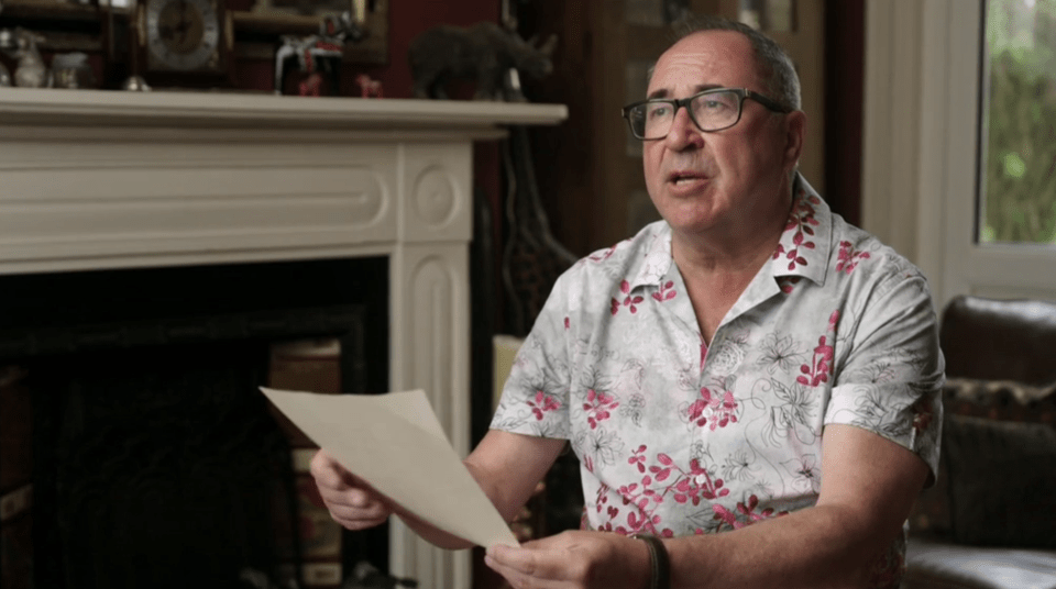 Man in a floral shirt reading a document.
