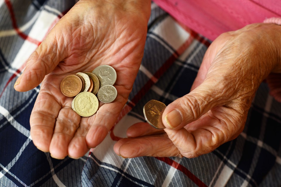 Close-up of elderly hands holding a small amount of coins.