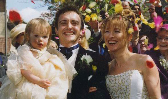 A wedding photo of a couple with their young daughter.