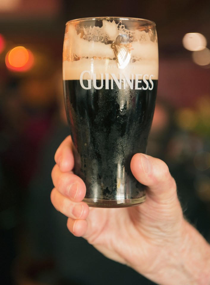 A hand holding a glass of Guinness.