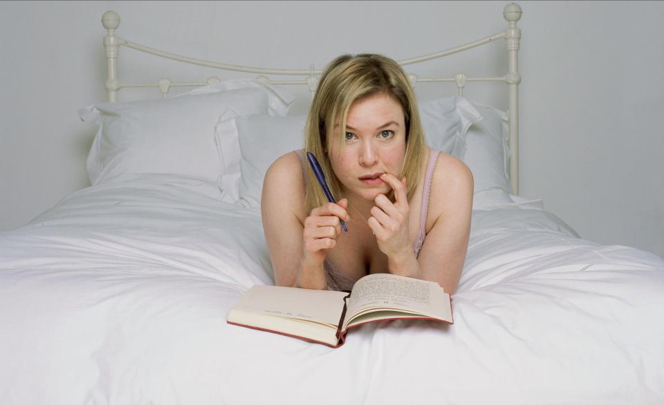 Renee Zellweger in bed writing in a journal.