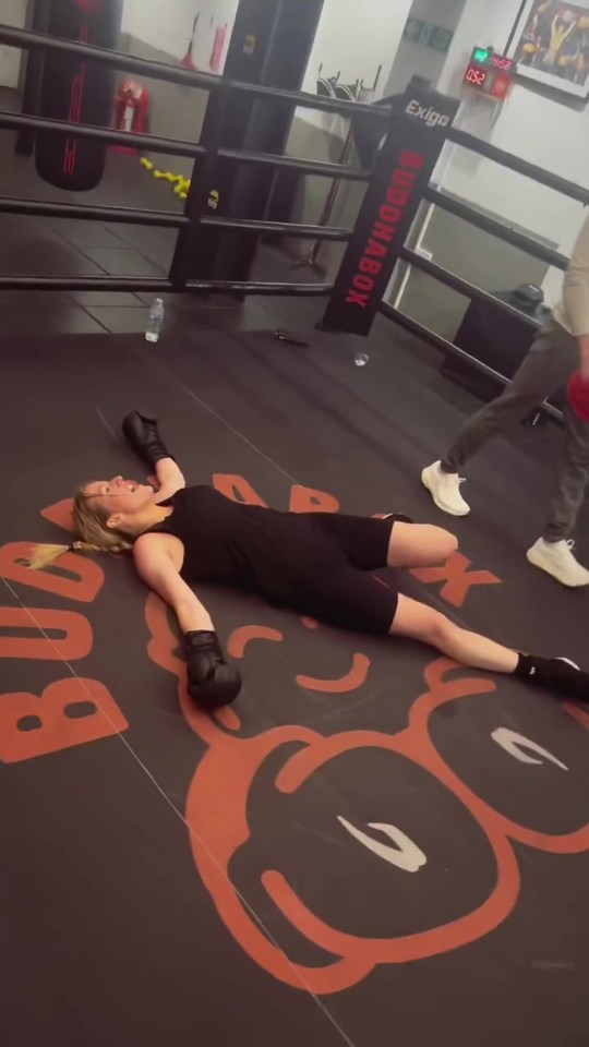 Woman lying on boxing ring floor after workout.