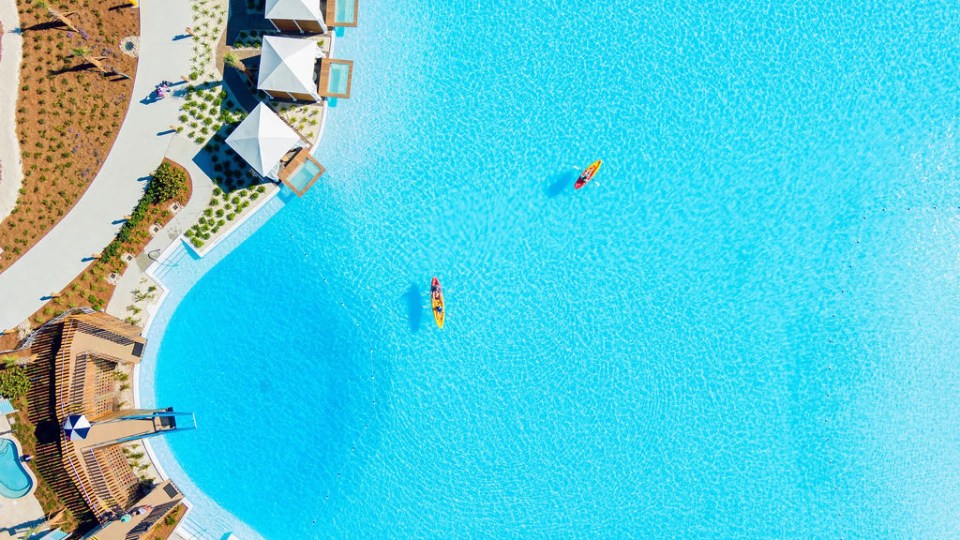 Aerial view of a large crystal-clear pool with two kayaks.