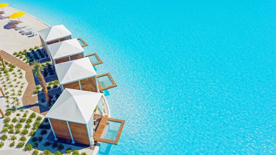 Aerial view of cabanas by a crystal-clear pool.