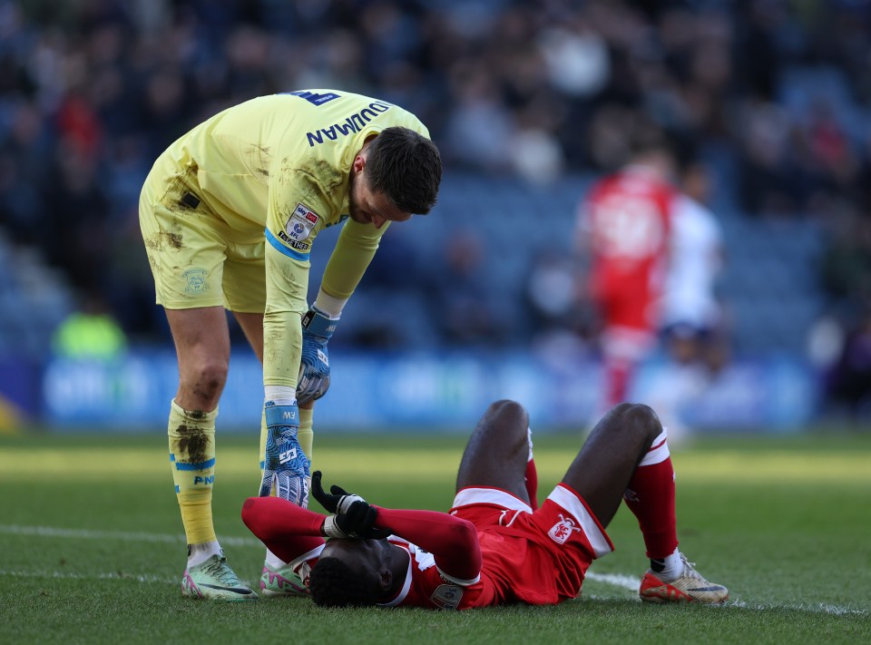 Soccer goalie attending to an injured player on the field.