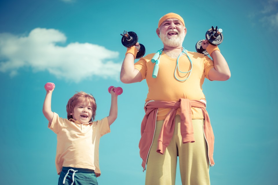 Grandfather and grandson lifting weights outdoors.