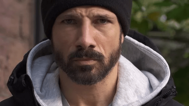 Close-up of a man with a beard wearing a black beanie and hooded jacket.