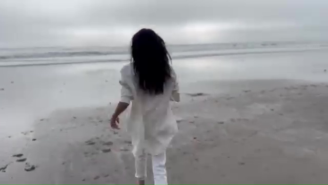 Woman in white walking away on a beach.