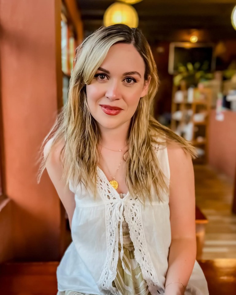 Woman with long blonde hair wearing a white crocheted top.