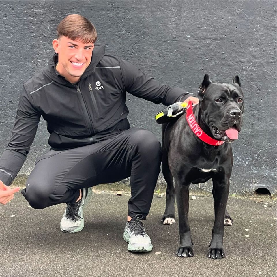 Jack Fincham crouching with his large black dog.