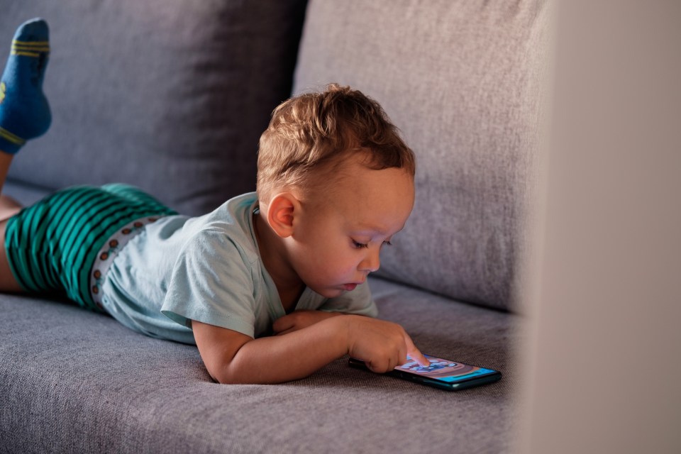 Toddler playing a mobile game on a smartphone.