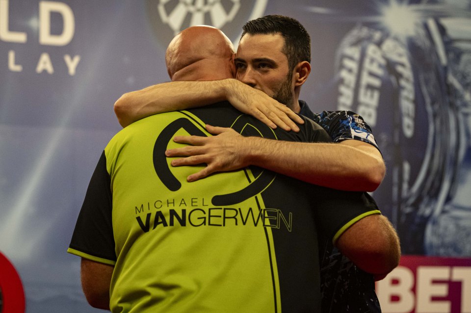 Luke Humphries and Michael van Gerwen embracing after a darts match.