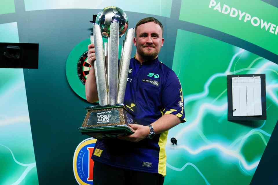 Luke Littler holding the Paddy Power World Darts Championship trophy.
