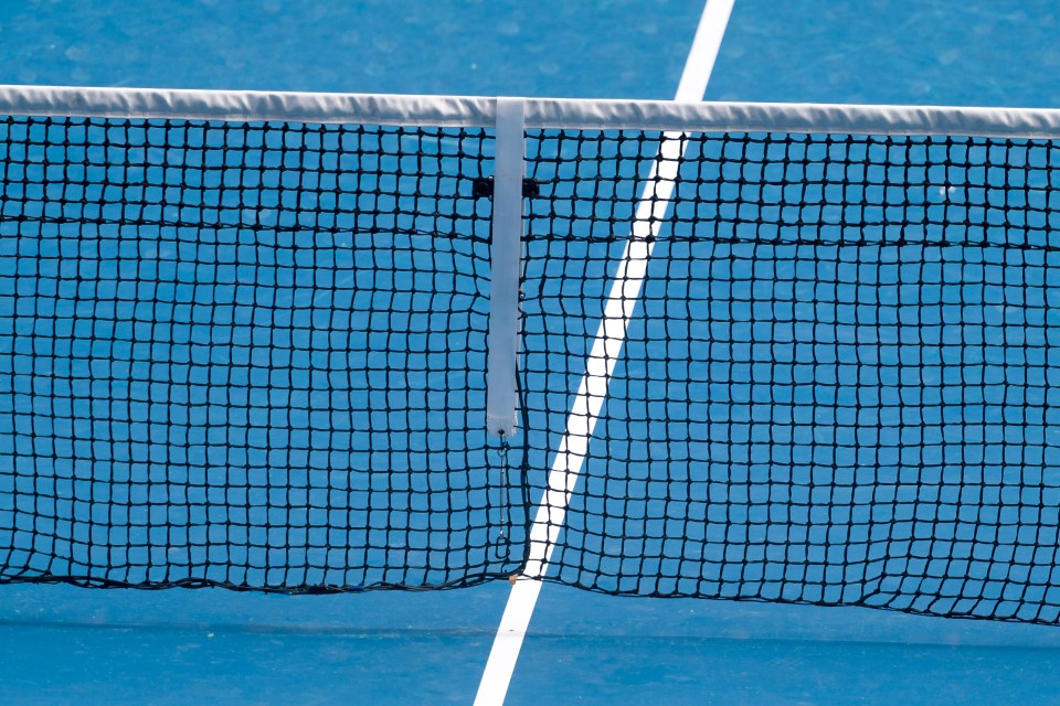 Damaged tennis net on a blue court.