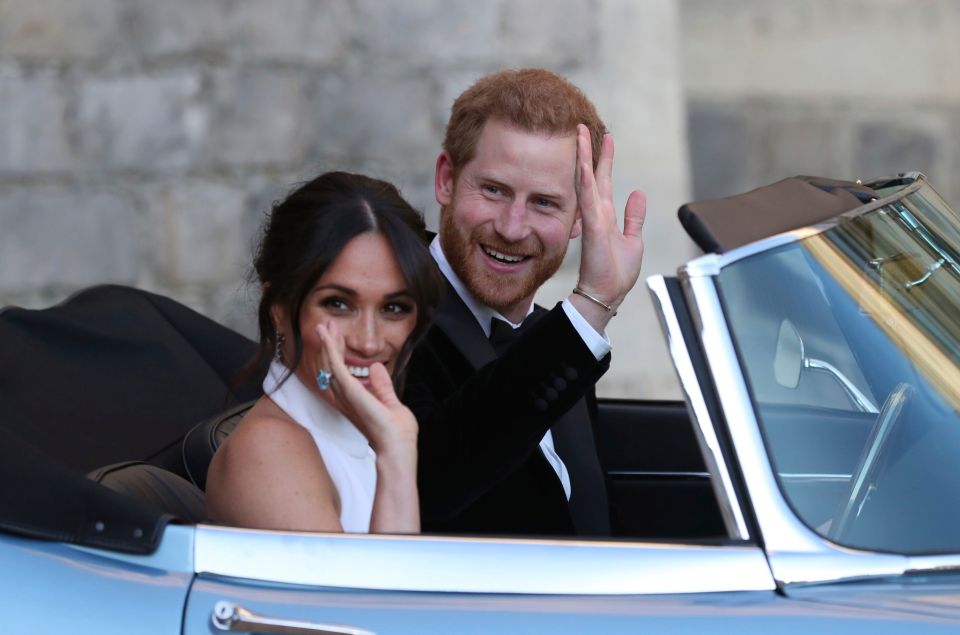 Prince Harry and Meghan Markle waving from a convertible car after their wedding.