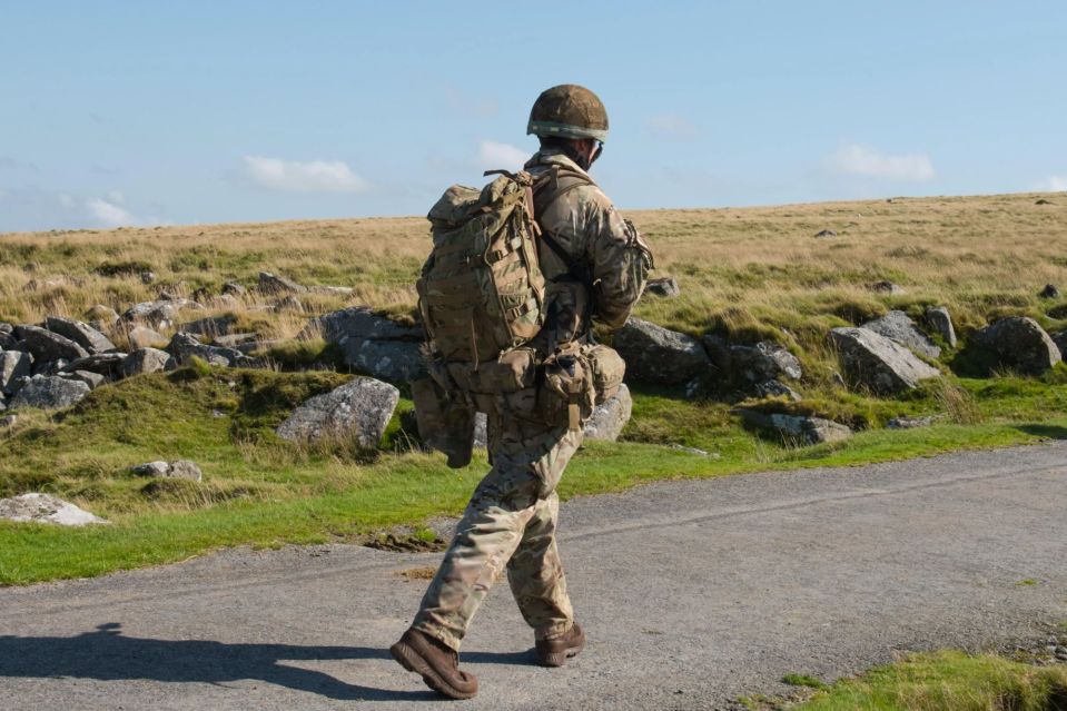 Soldier walking on a road with a backpack.
