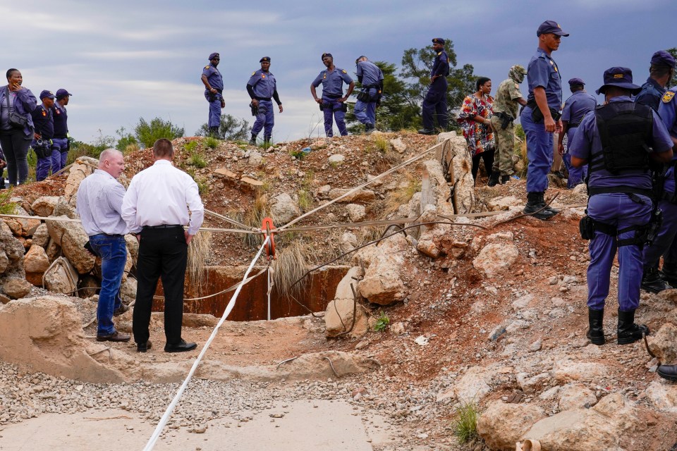 Police officers and private security personnel at a collapsed gold mineshaft.