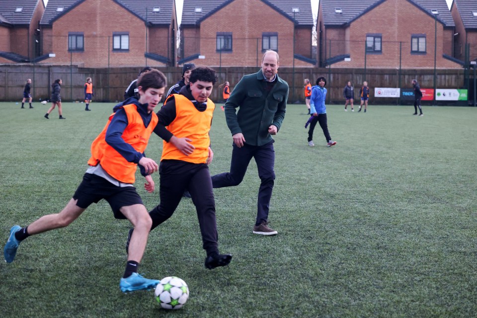 The Prince of Wales playing soccer with young people.