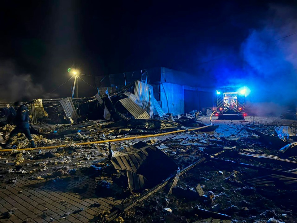 A bombed-out building at night with emergency responders present.