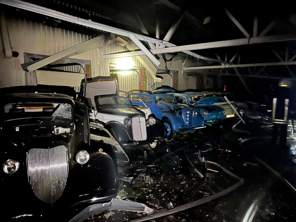 Bombed classic cars in a damaged building.