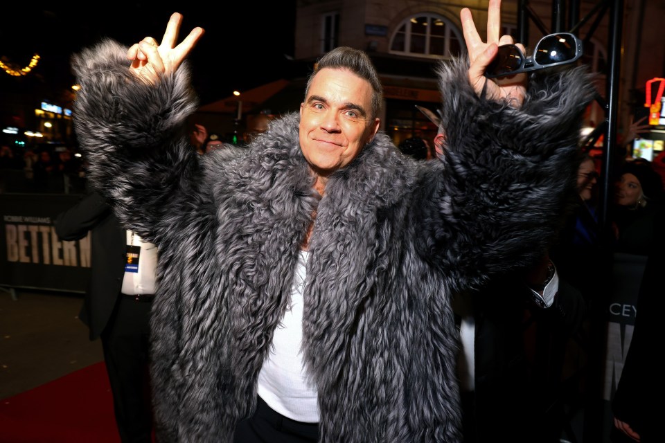 Robbie Williams at a film screening, giving a peace sign.