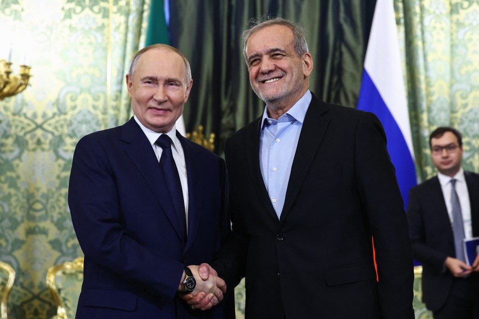 Vladimir Putin and Masoud Pezeshkian shaking hands.
