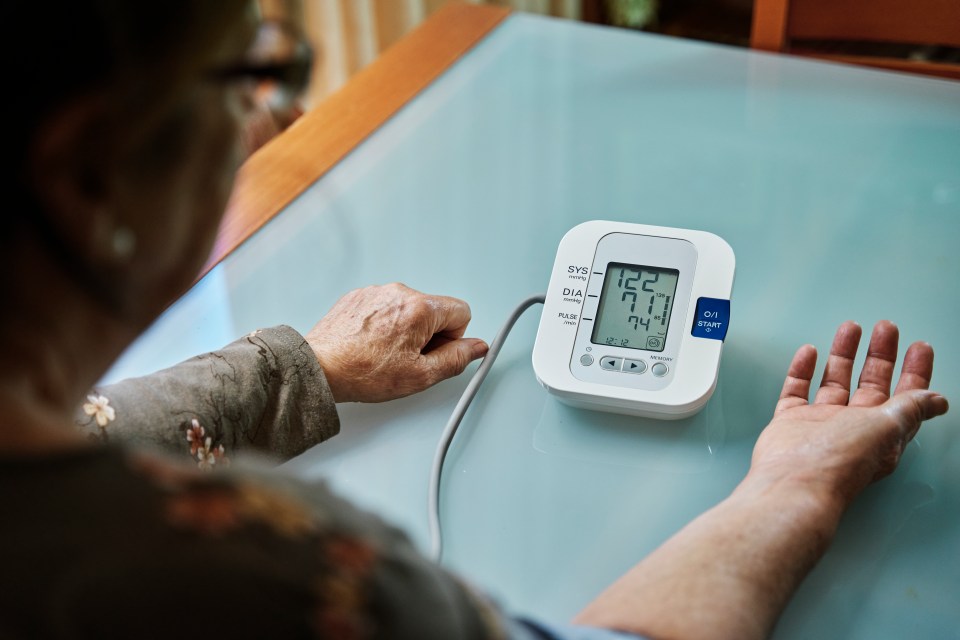 Senior woman checking her blood pressure using a digital monitor.