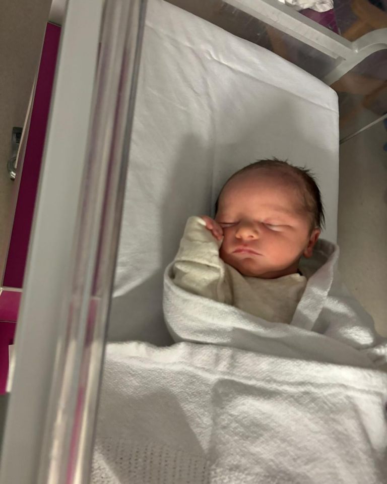 Newborn baby sleeping in a hospital crib.