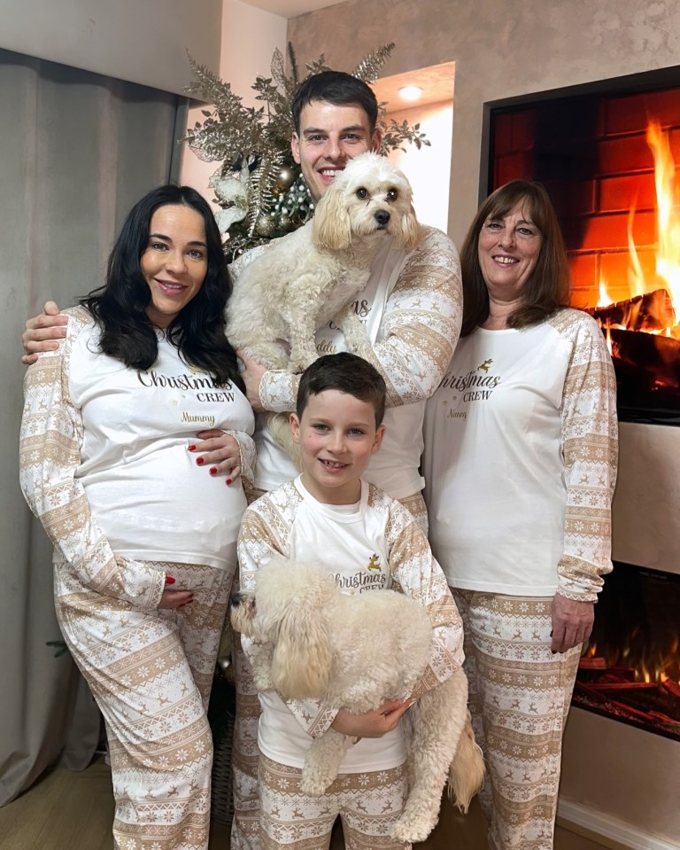 Family in matching Christmas pajamas with two dogs.