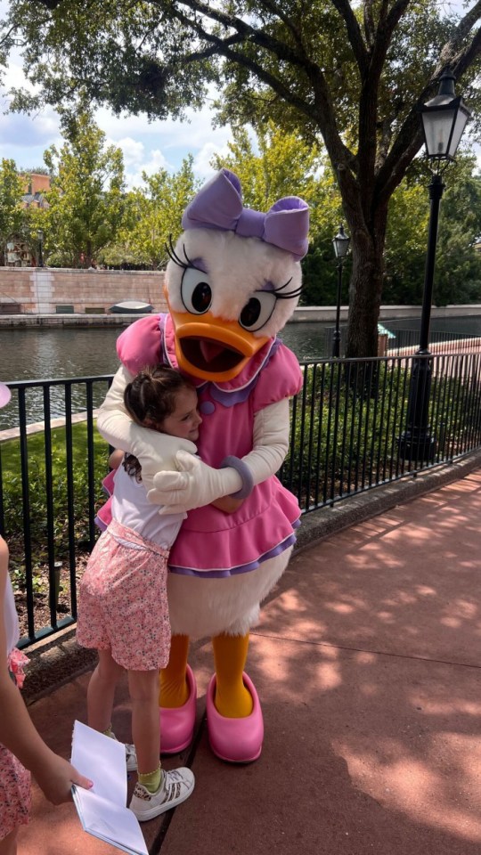 A young girl hugs Daisy Duck at Disney.