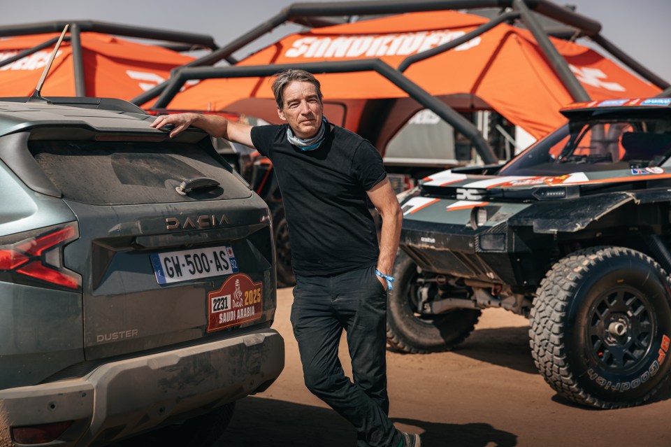 Man leaning on a Dacia Duster rally car in Saudi Arabia.