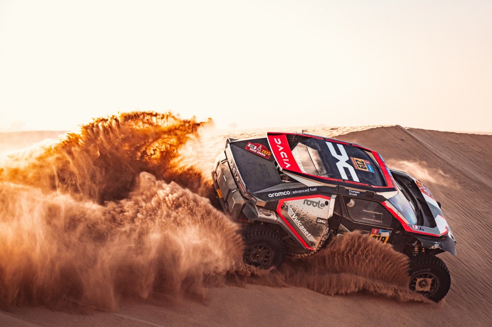 Race car kicking up sand in a desert.