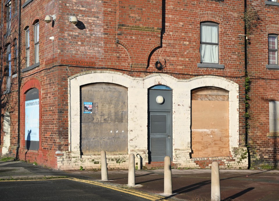 Boarded-up shops on a brick street.
