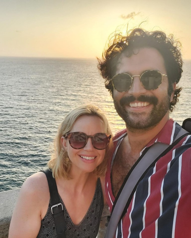 Couple smiling at sunset over ocean.