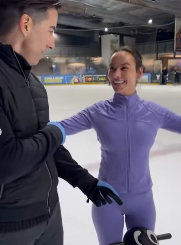 A man assists a woman ice skating.
