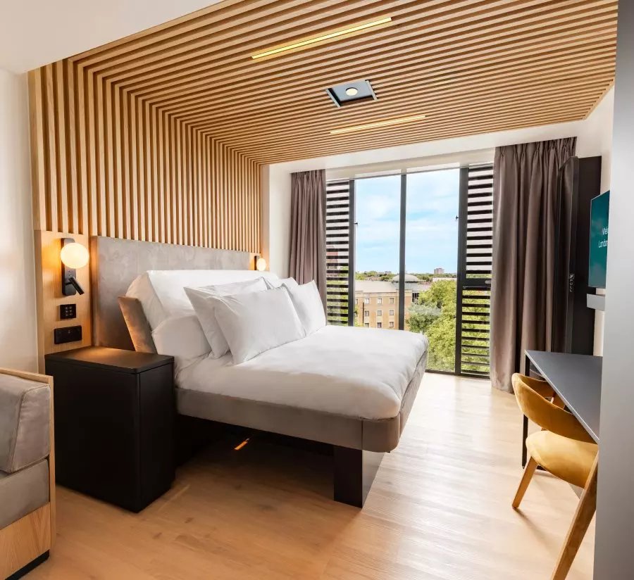 Modern hotel room with a bed and city view.