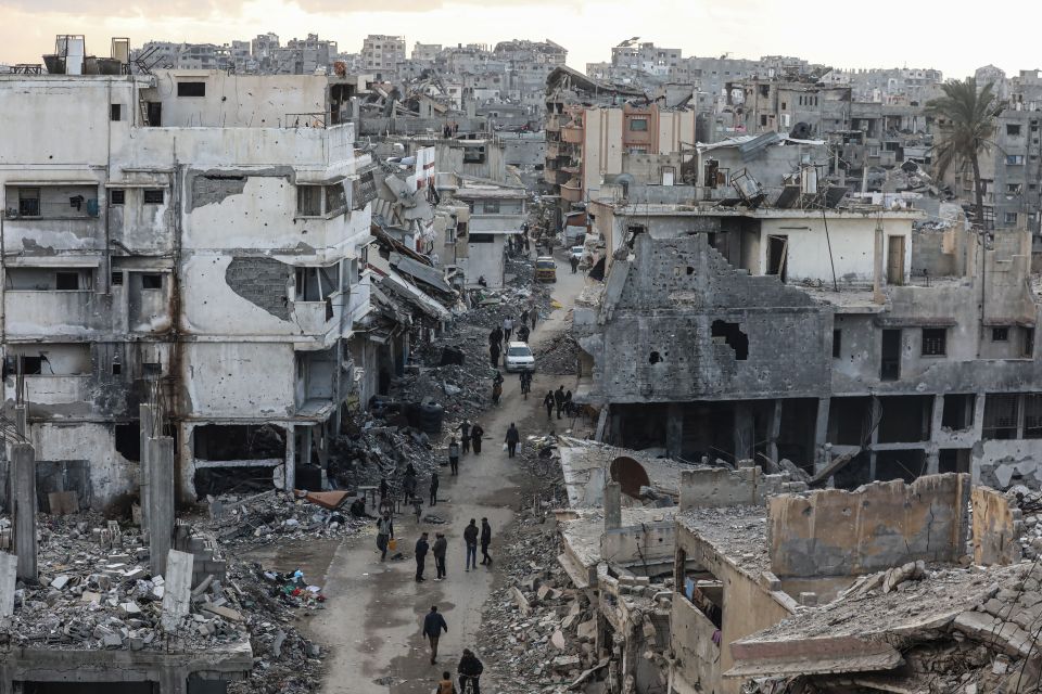 People walk through rubble-strewn streets in Gaza City following a ceasefire.