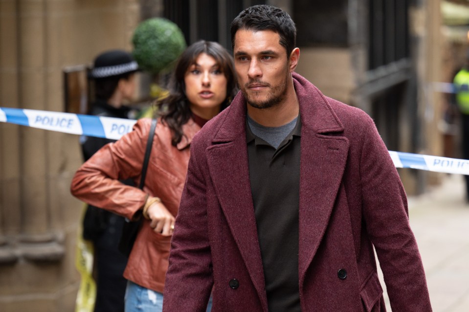 Man in a burgundy coat walking past police tape.