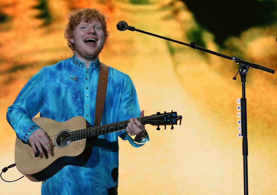 Ed Sheeran performing on stage with a guitar.