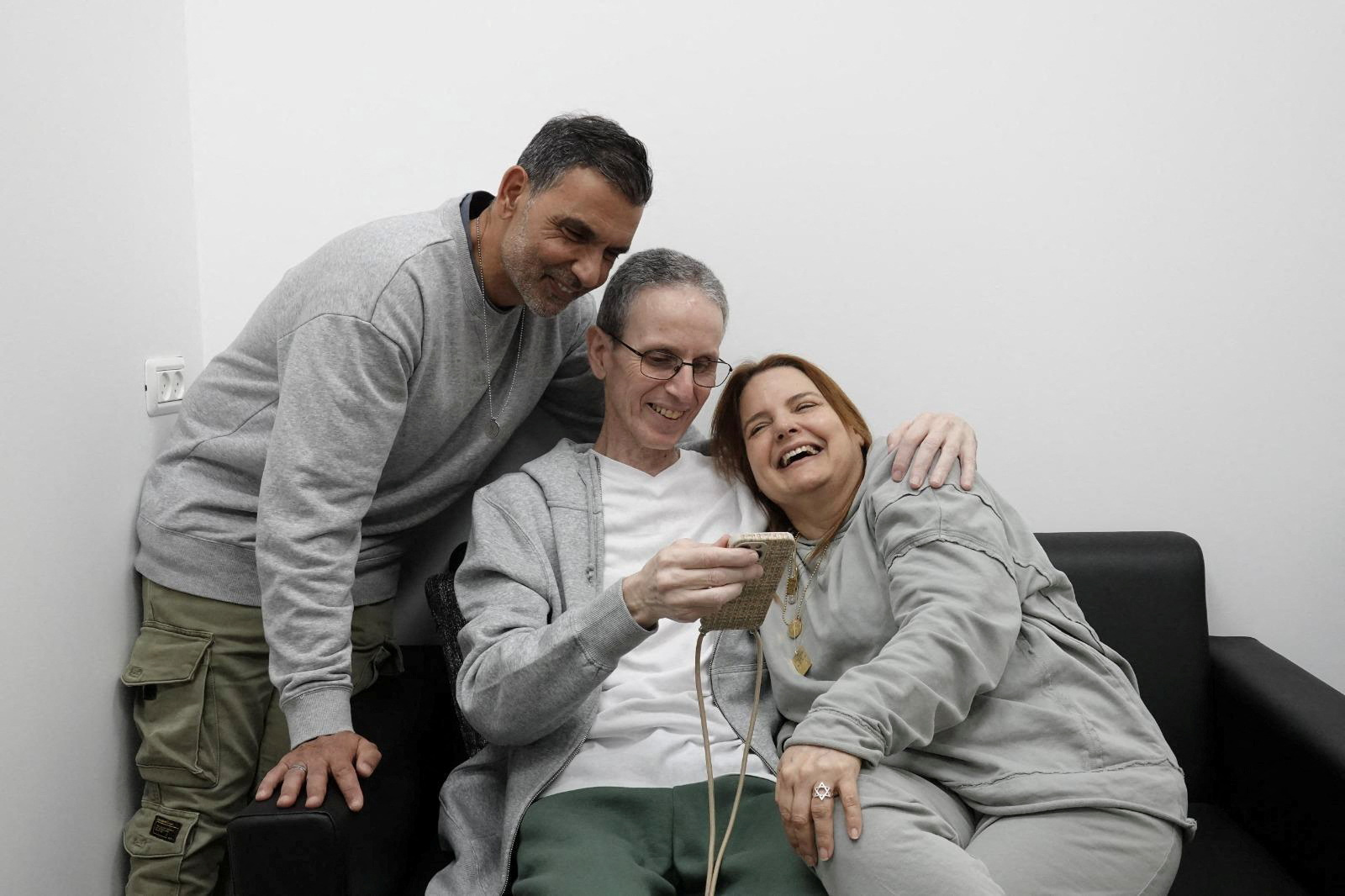 Released hostage embracing loved one while looking at a phone.