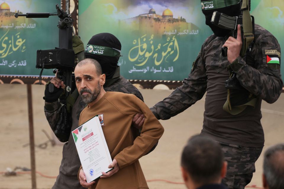 Man in brown shirt being interviewed by a person in camouflage.