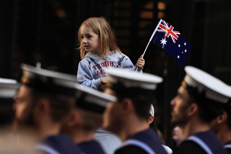 Girl holding Australian flag at Anzac Day parade.