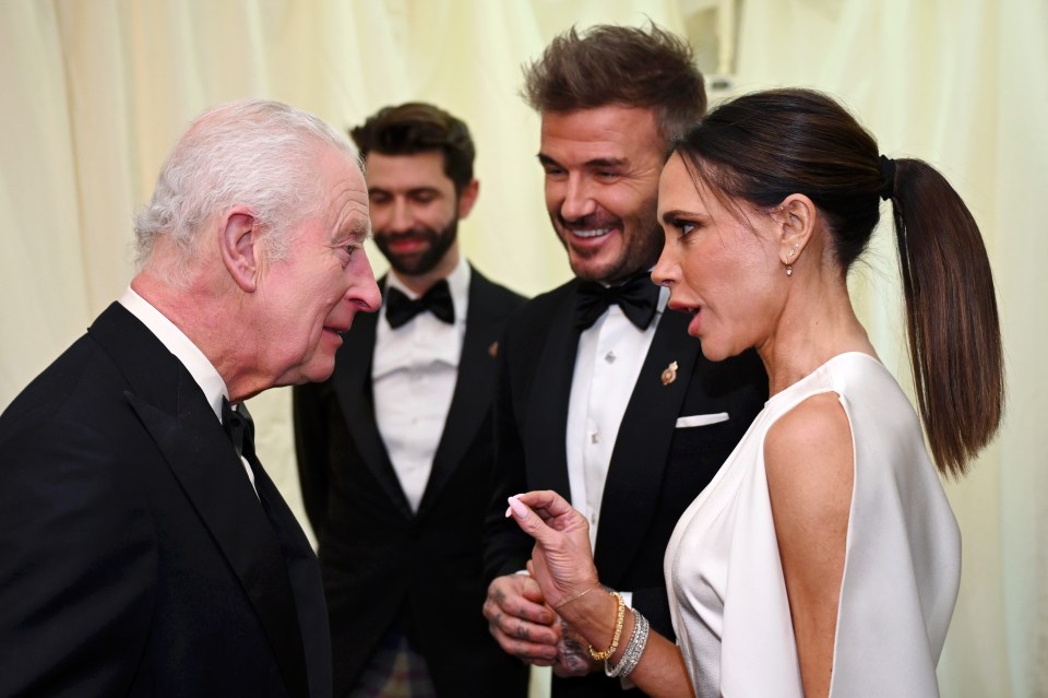 King Charles III and Victoria Beckham in conversation at a dinner.