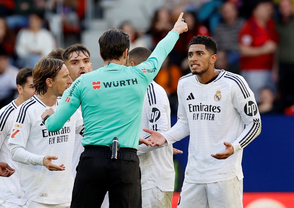 Jude Bellingham of Real Madrid receives a red card from a referee.