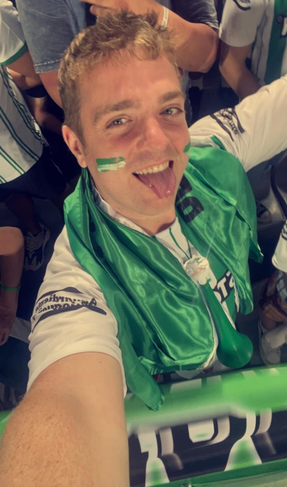 Selfie of a man at a sporting event wearing a green scarf.