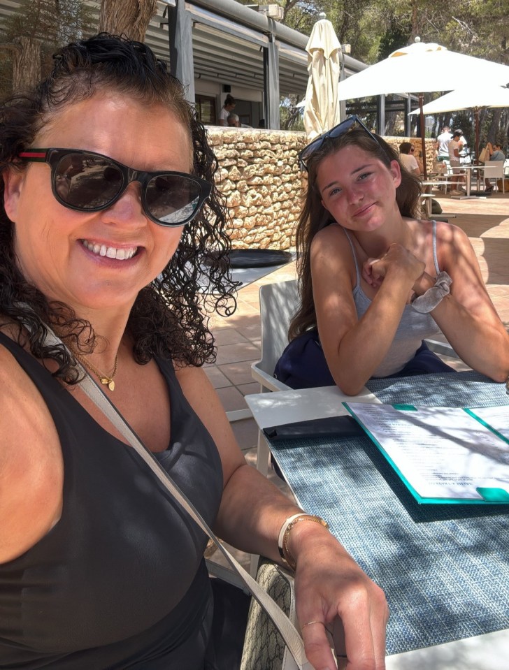 Woman and teenage girl sitting at an outdoor cafe table.